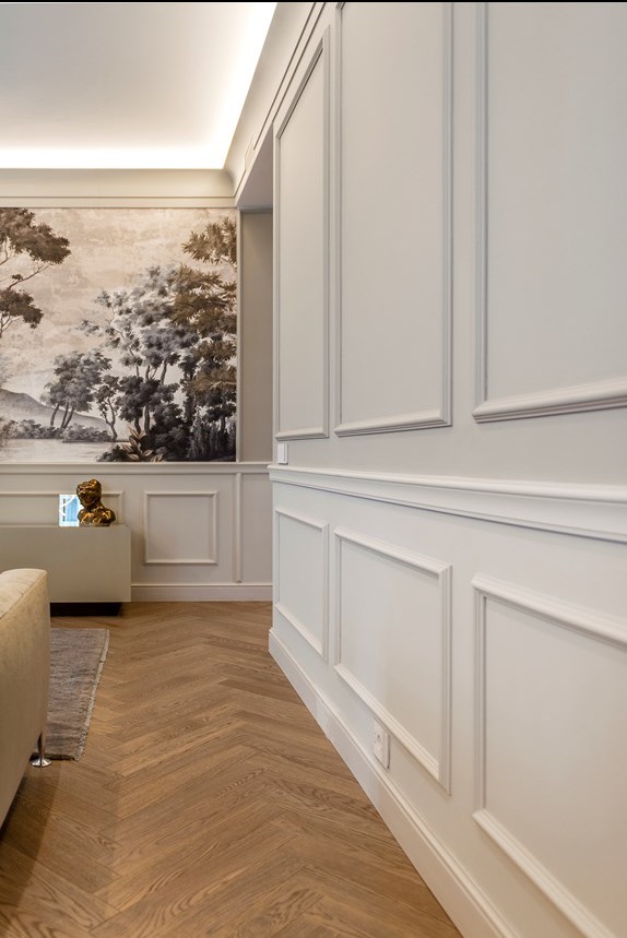 Eleganckie wykończenie wnętrza z panelami ściennymi w stylu klasycznym, parkietem w jodełkę i dekoracyjną tapetą z motywem pejzażu. Subtelne oświetlenie LED.