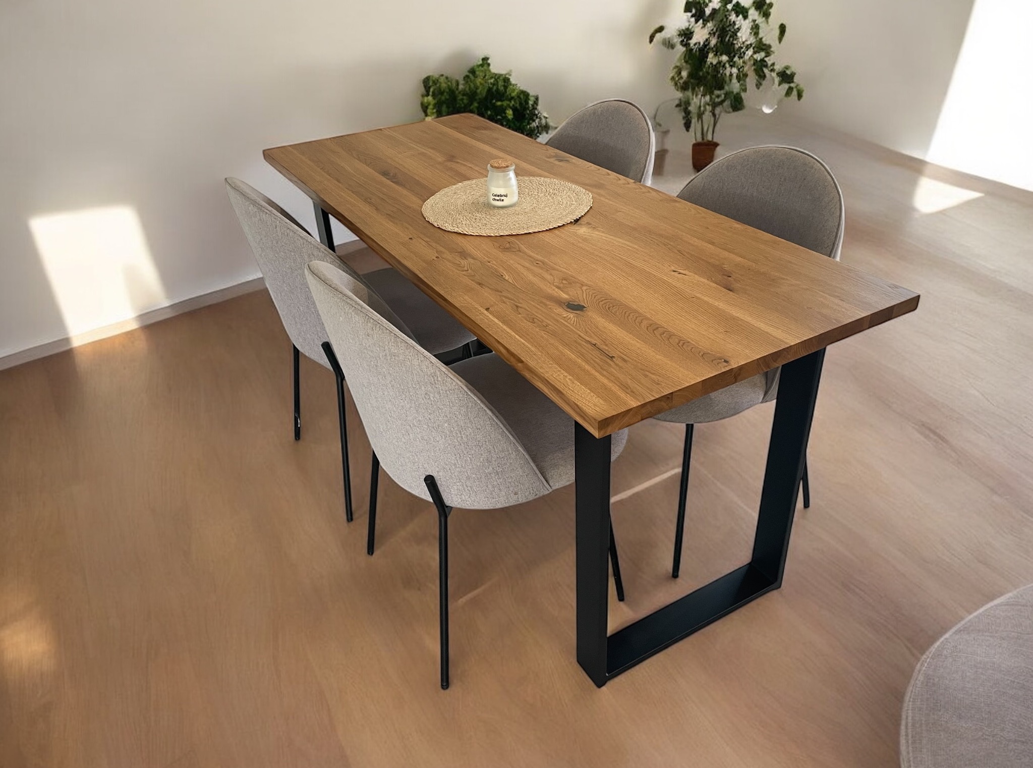 Stół z blatem z litego drewna dębowego na czarnych, metalowych nogach w kształcie litery U, otoczony krzesłami w szarym obiciu, na podłodze z paneli.