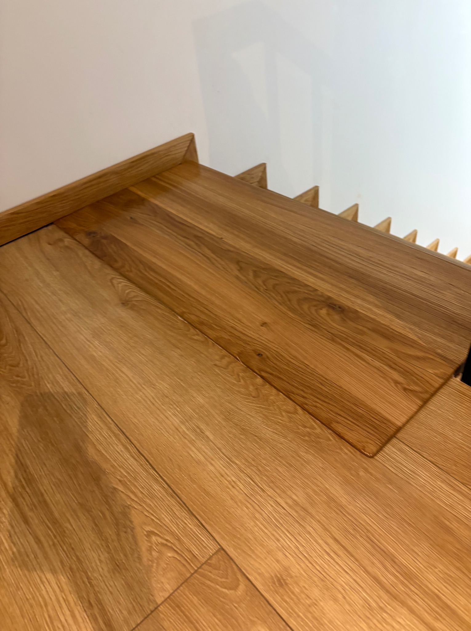 Detale wykończenia schodów drewnianych z widocznymi stopniami i podstopnicami, wykonane z jasnego drewna dębowego, z bliska, z minimalistycznym wykończeniem.