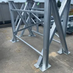 Srebrna, ocynkowana konstrukcja stalowa z profili zamkniętych, spawana, z podstawami przykręcanymi do podłoża. W tle widoczne elementy konstrukcyjne.