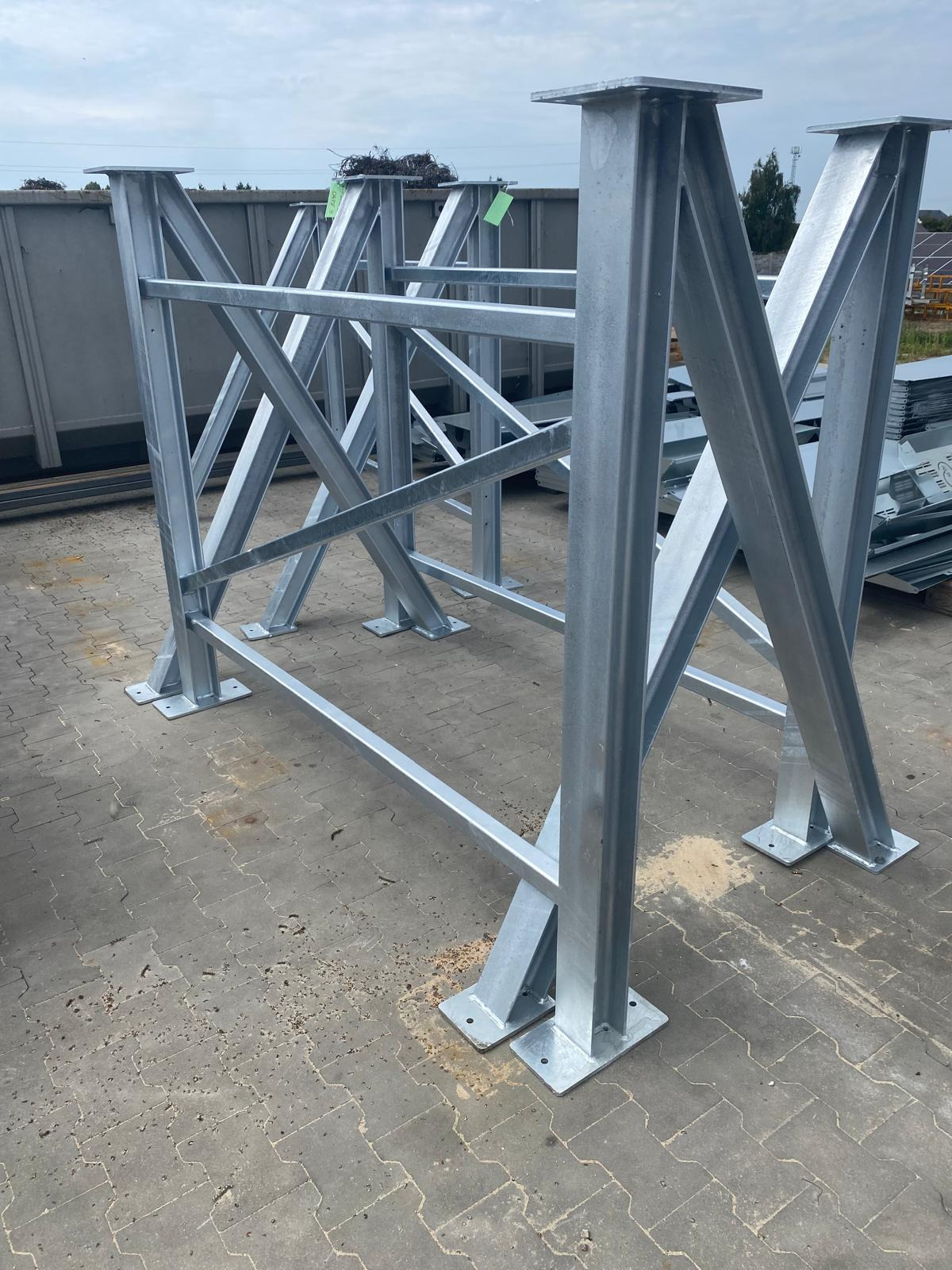 Srebrna, ocynkowana konstrukcja stalowa z profili zamkniętych, spawana, z podstawami przykręcanymi do podłoża. W tle widoczne elementy konstrukcyjne.