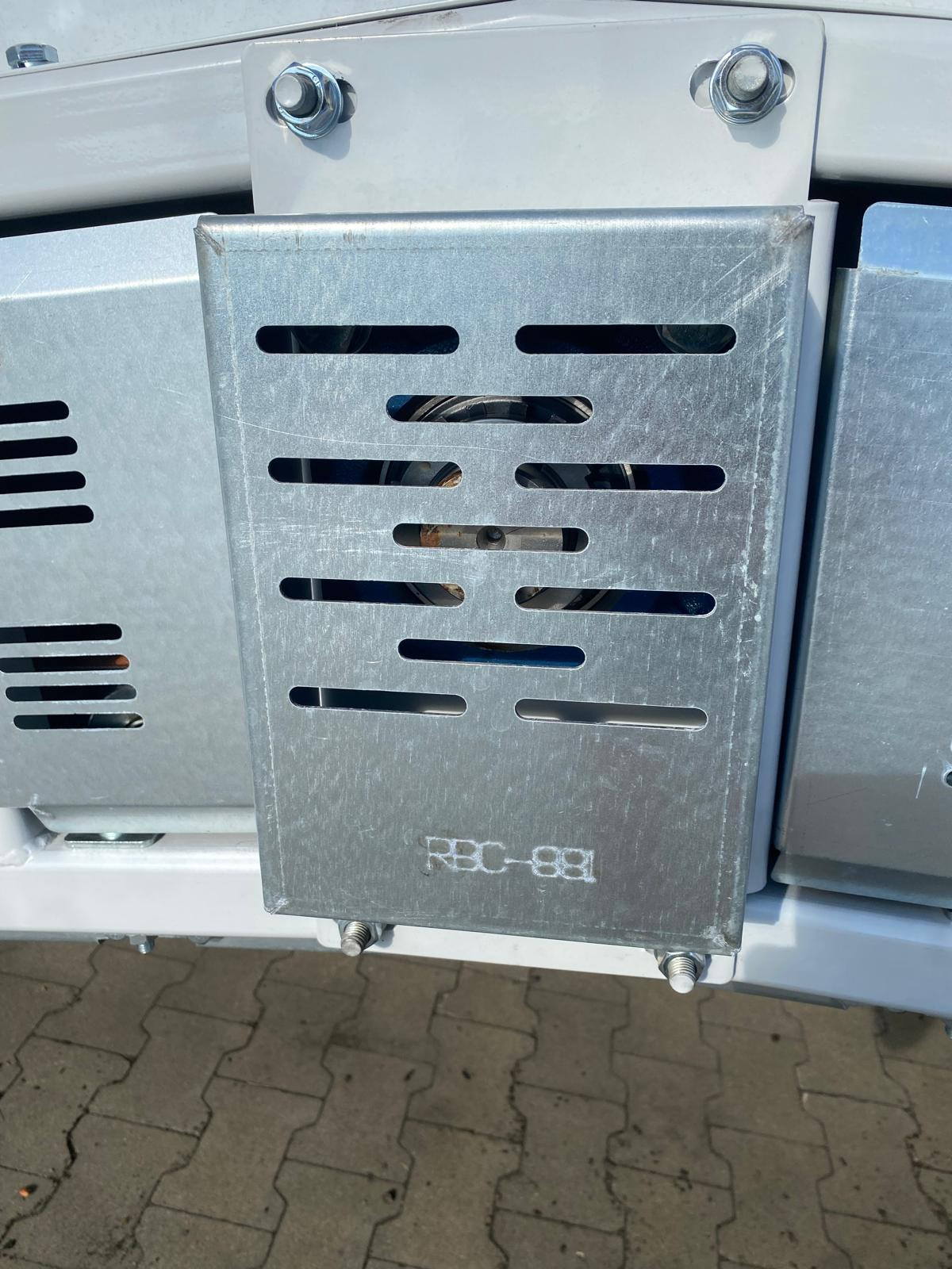 Metalowa osłona z otworami wentylacyjnymi, przymocowana śrubami do białej konstrukcji. Widoczne przewody wewnątrz i oznaczenie 'RBC-881'.