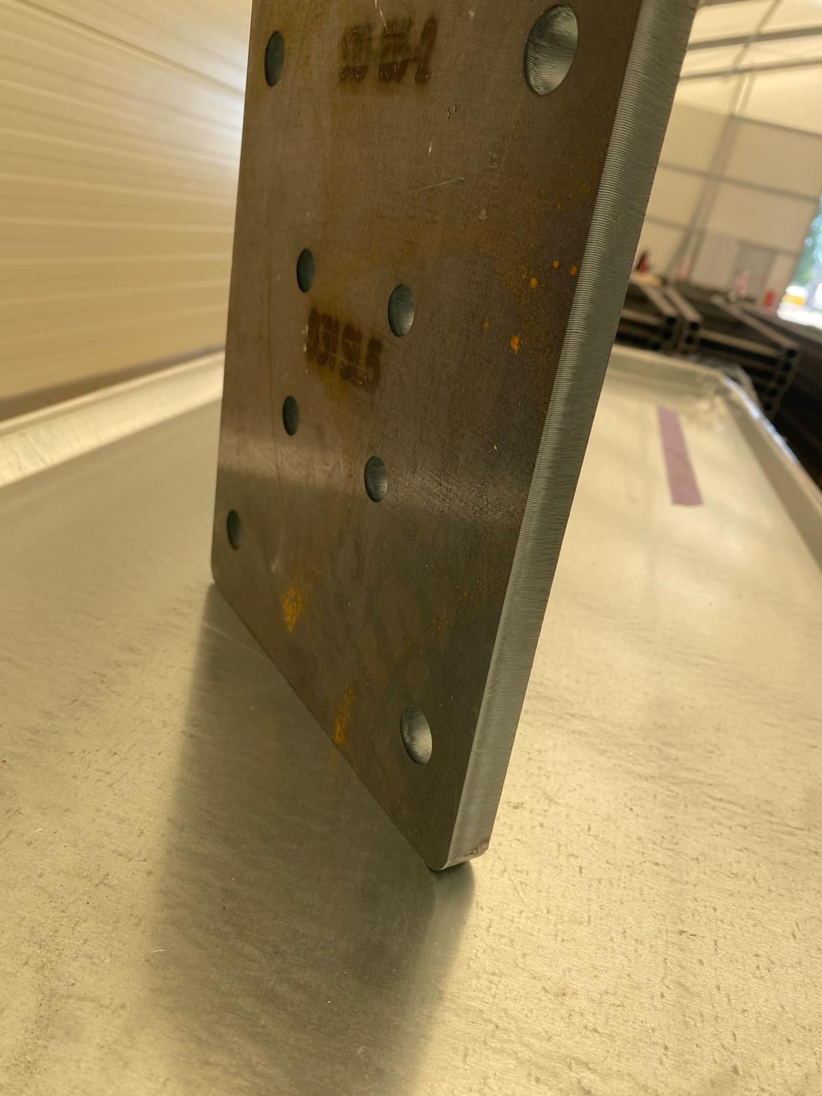 Metalowa płyta z otworami, obróbka skrawaniem, szlifowane krawędzie. Precyzyjne wykonanie w Czastary. Widoczne oznaczenia na powierzchni.