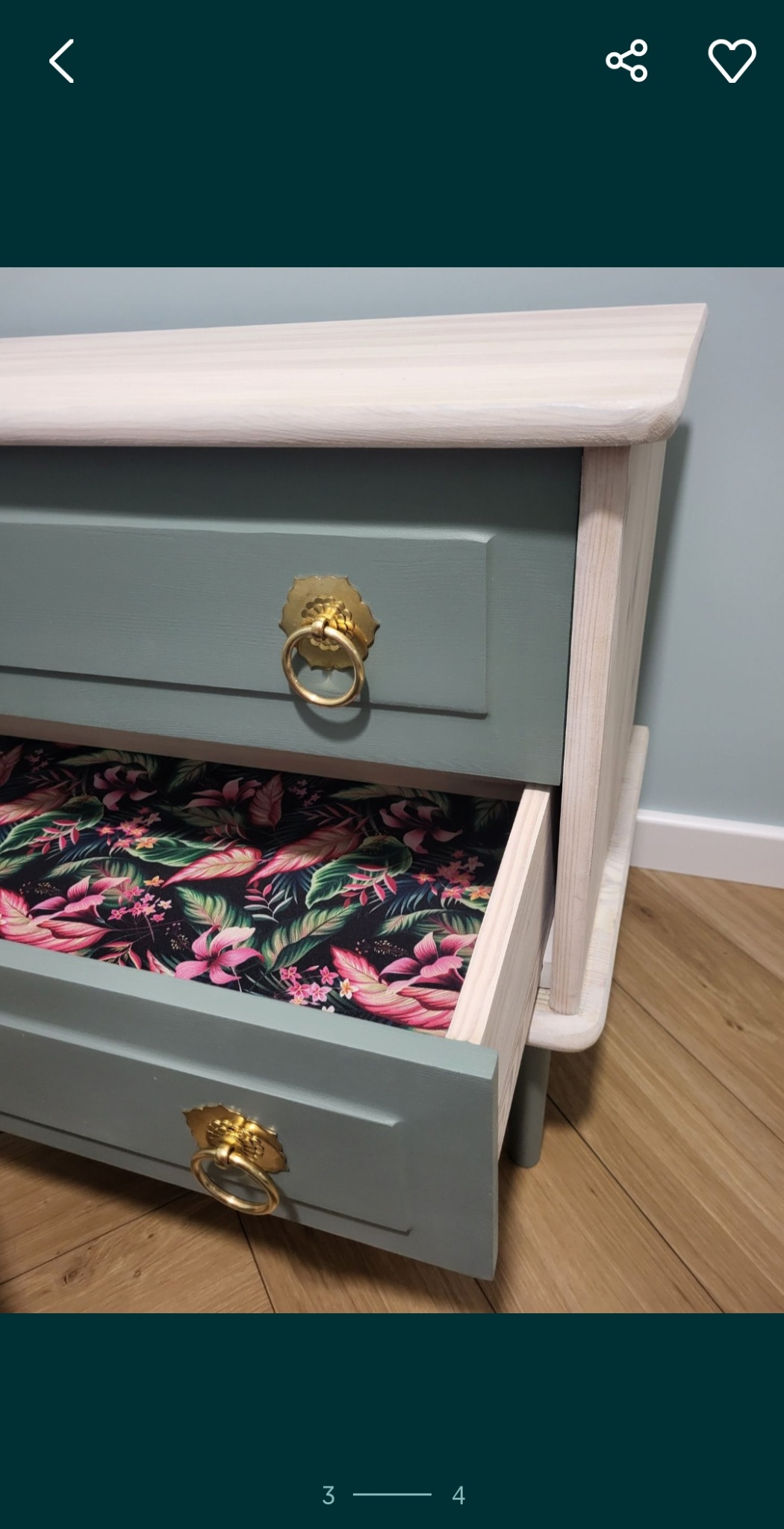 Komoda po renowacji z otwartą szufladą, wnętrze wyłożone wzorzystą tapetą. Odnowiony mebel w odcieniach szarości i zieleni, złote uchwyty.