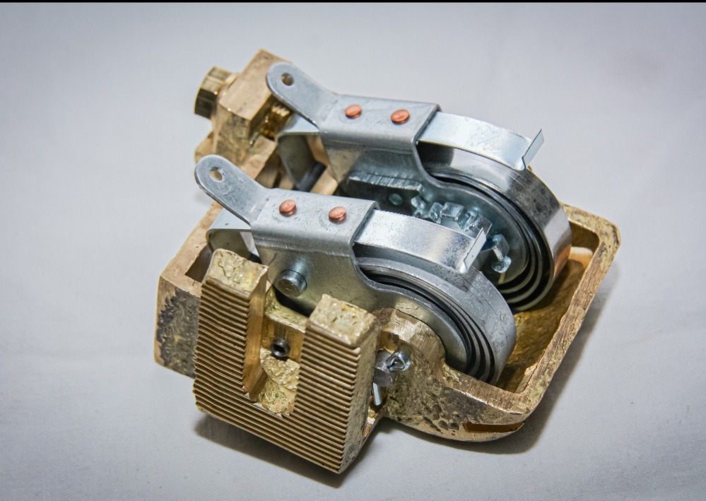 Precyzyjnie wykonany element metalowy z mosiądzu i stali nierdzewnej, detal obróbki skrawaniem we Wrocławiu. Widoczne rowki i mocowania.