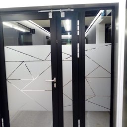 BAD BOYS AGENCY SPÓŁKA Z OGRANICZONĄ ODPOWIEDZIALNOŚCIĄ - Czarne drzwi biurowe z matową folią w geometryczne wzory, widoczne wnętrze z oświetleniem LED. Minimalistyczny design, nowoczesne wykończenie.
