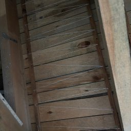 Expo-Activ - Drewniana konstrukcja poddasza z naciągniętymi, cienkimi drutami, prawdopodobnie pod sufitem napinanym. Widoczne elementy drewniane i przewody elektryczne.