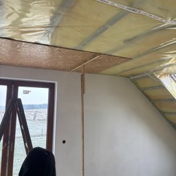 Expo-Activ - Izolacja poddasza z folią paroizolacyjną Isover Vario KB 1, widoczne płyty OSB i drabina przy oknie. Prace wykończeniowe na poddaszu.