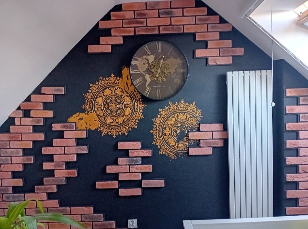 Ściana w pokoju na poddaszu z dekoracyjną cegłą, zegarem i wzorami mandali. Grzejnik na ścianie. Oryginalny wystrój.