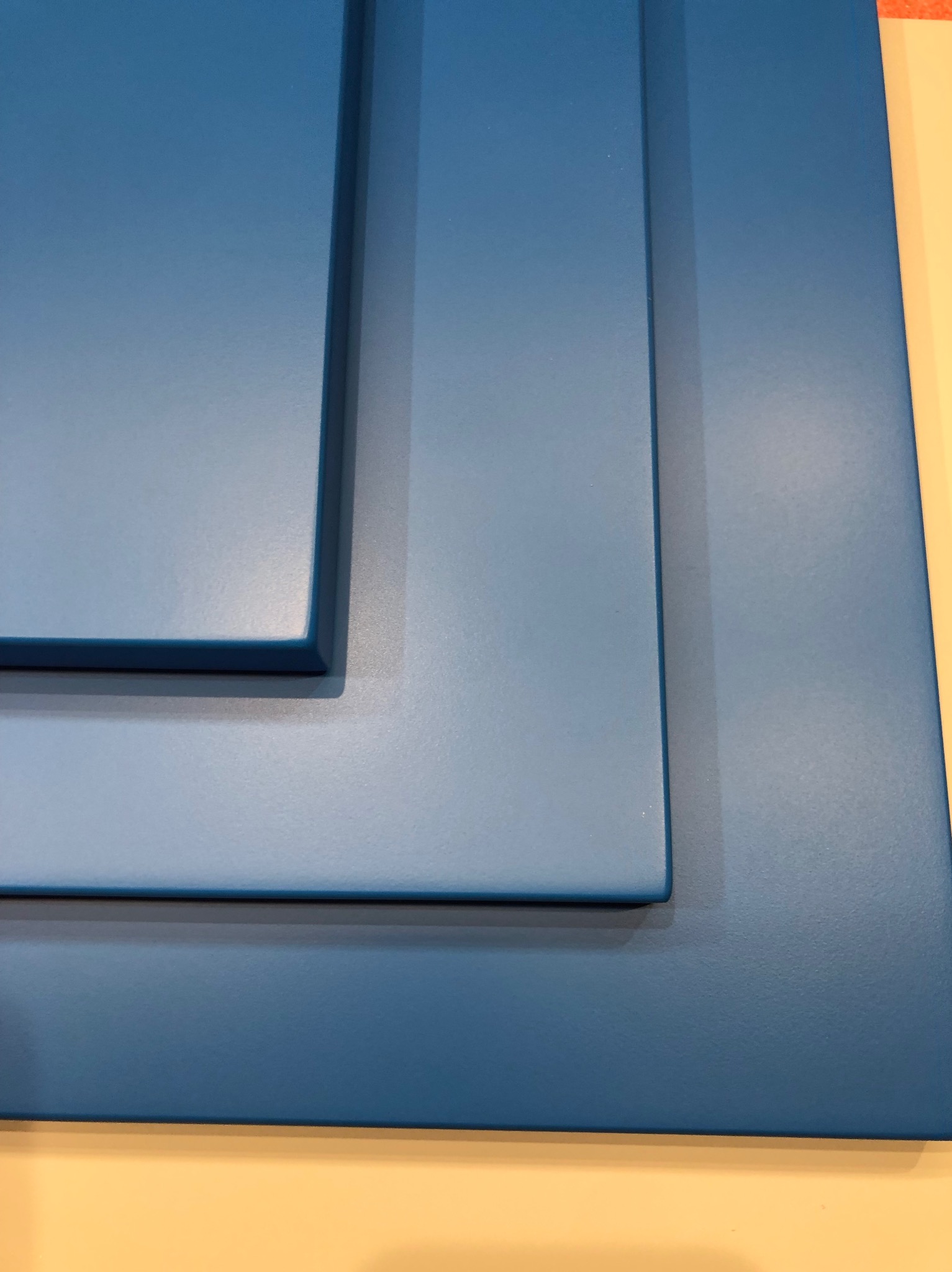 Niebieski panel meblowy z frezowanymi krawędziami, prezentujący detale wykończenia i głębię koloru, na jasnym tle.