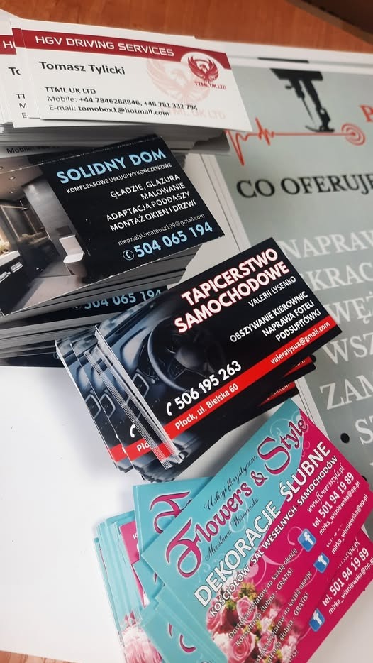 Stos wizytówek różnych firm, w tym z usługami wykończeniowymi, tapicerstwa samochodowego i dekoracji ślubnych, ułożonych na białym tle. Różne wzory i kolory.