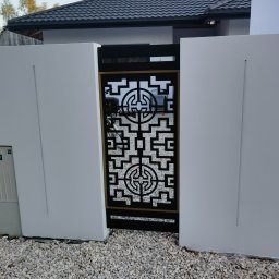 Rafał Adamczuk ALLStal - Nowoczesna brama wjazdowa z dekoracyjnym, geometrycznym wzorem w kolorze czarnym, osadzona między białymi, minimalistycznymi ścianami na tle szarej dachówki.