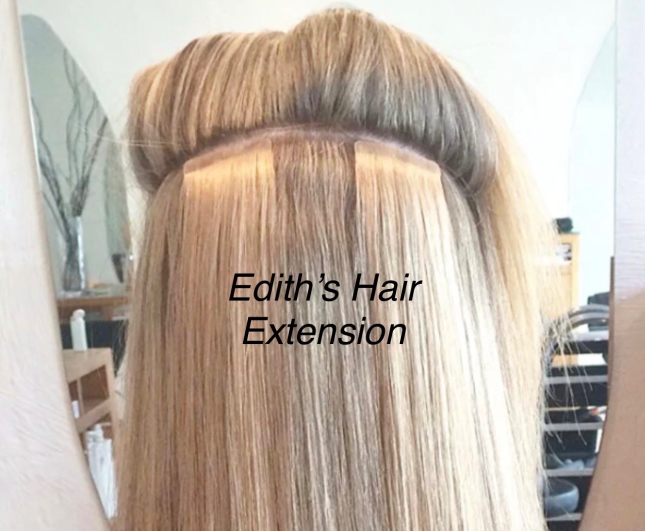 Blond włosy z doczepami na taśmach, widoczne łączenia u nasady. Ujęcie z tyłu głowy, w tle lustro i fragment wnętrza. Edith's Hair Extension.