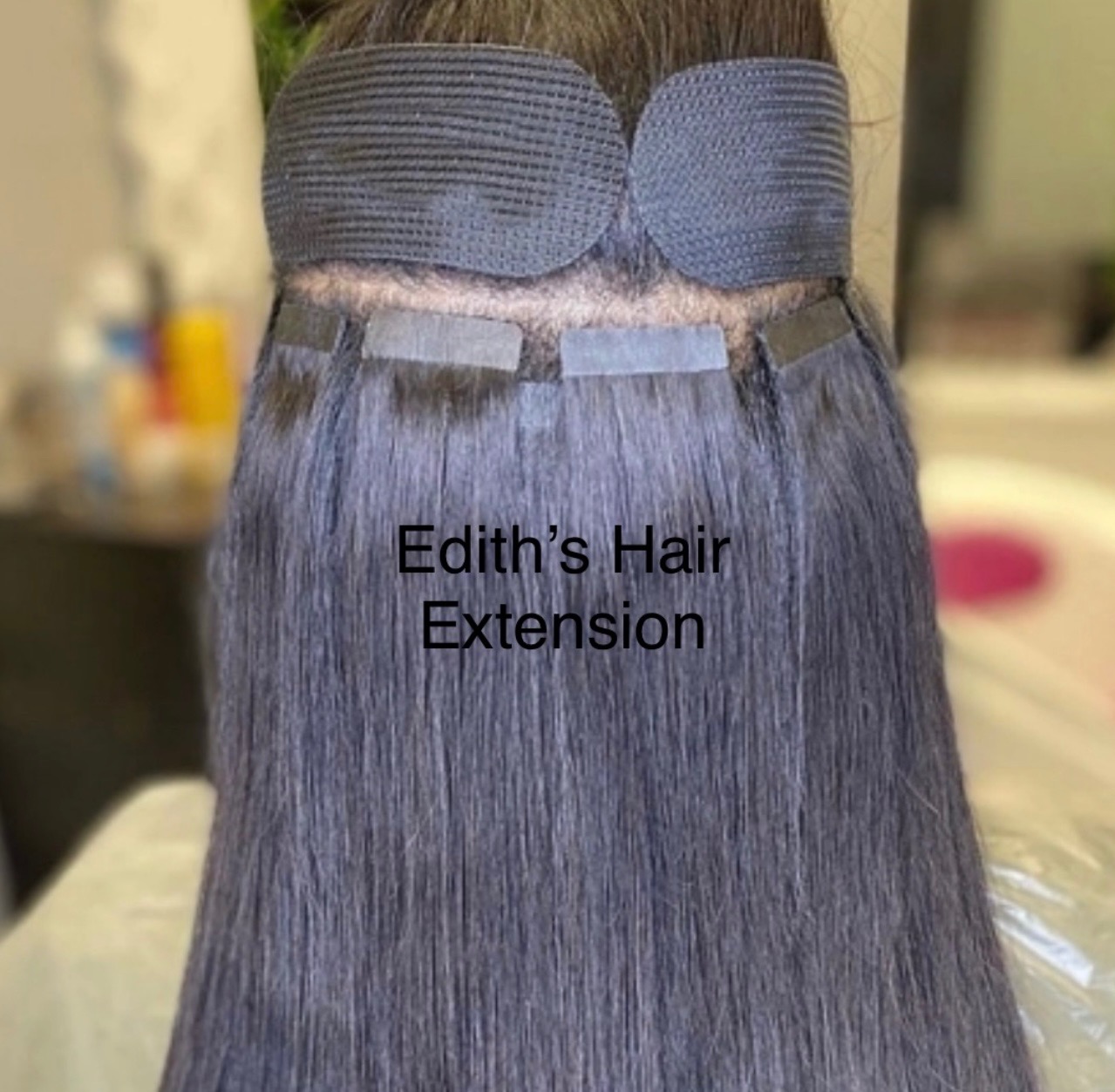 Aplikacja doczepianych włosów metodą tape-on, widoczne paski mocujące u nasady. Ciemne, proste włosy. Elastyczna opaska zabezpieczająca. Edith's Hair Extension.