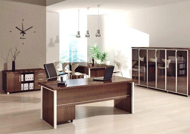 Nowoczesne biuro z biurkiem, laptopem, szafą z przeszklonymi drzwiami i zegarem na ścianie. Stonowana kolorystyka brązu i bieli, minimalistyczny design.