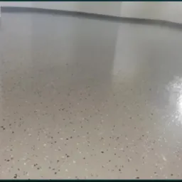 Błyszcząca, szara posadzka żywiczna z czarnymi i białymi elementami dekoracyjnymi w pomieszczeniu. Realizacja w Piekielniku.