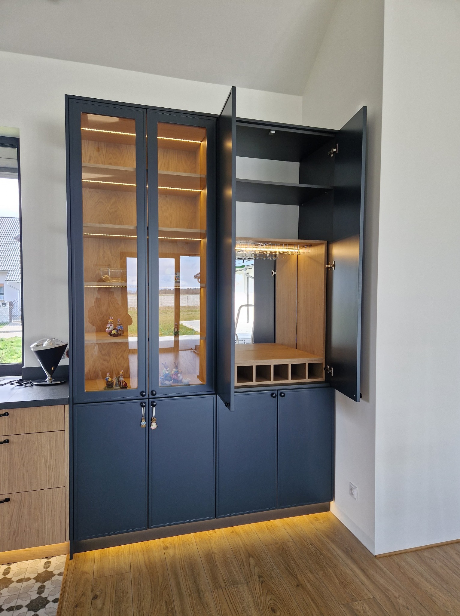 Elegancka szafa na wymiar w Łodzi z oświetleniem LED, otwarte półki na alkohol i szklane drzwi. Nowoczesny design, drewniane wykończenie wewnątrz.