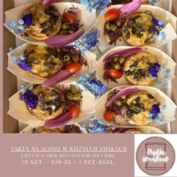 Tarty na słono, dekorowane kwiatami, oliwkami i pomidorkami cherry, ułożone w drewnianych łódeczkach. Elegancki catering na imprezę.