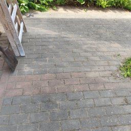 Kamil lisewski - Ułożona kostka brukowa na zewnątrz, z drabinką i zielenią w tle. Widoczny fragment łopaty. Kąt ujęcia z góry, naturalne oświetlenie.