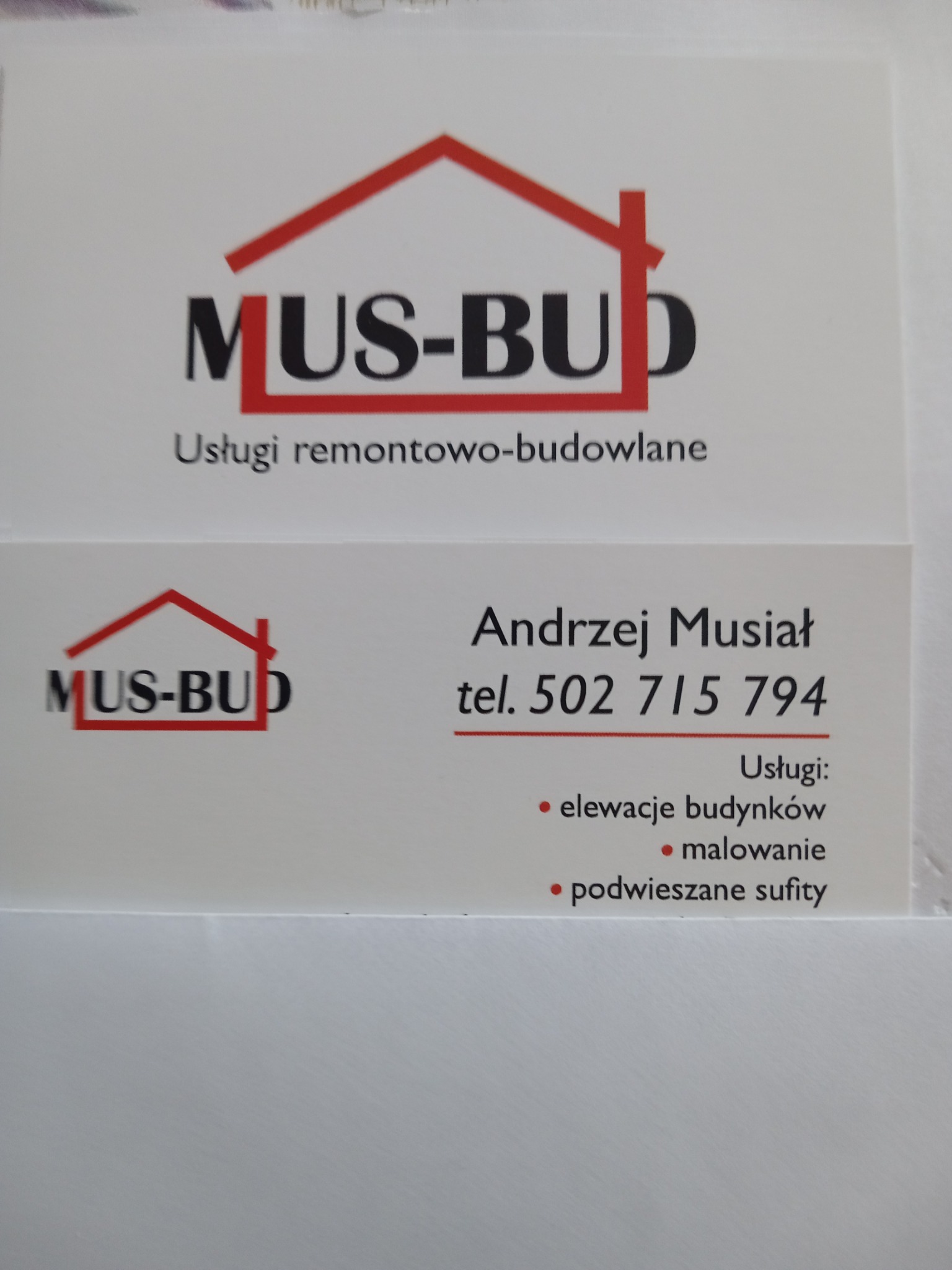 Wizytówka firmy remontowo-budowlanej MUS-BUD z czerwonym logo domu, oferującej elewacje budynków, malowanie i podwieszane sufity. Kontakt: Andrzej Musiał, tel. 502 715 794.