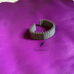 Bransoleta z metalowej siatki na fioletowym tle, z widocznym logo 'Titanium Soul'. Precyzyjne wykonanie, gęsty splot. Unikalny design.