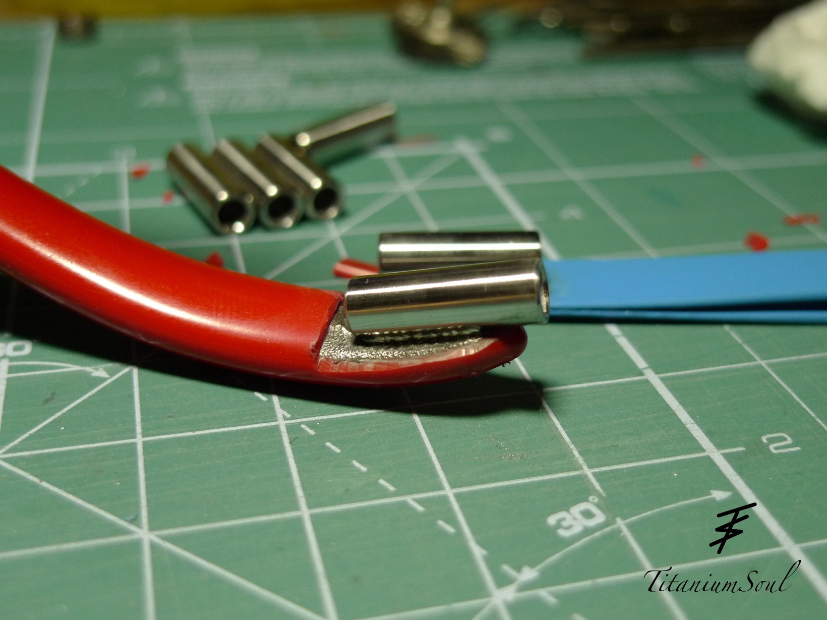 Zaciskanie tulejki na przewodzie w Tychach. Widoczne narzędzia i materiały na macie. Precyzyjne łączenie elementów elektrycznych.