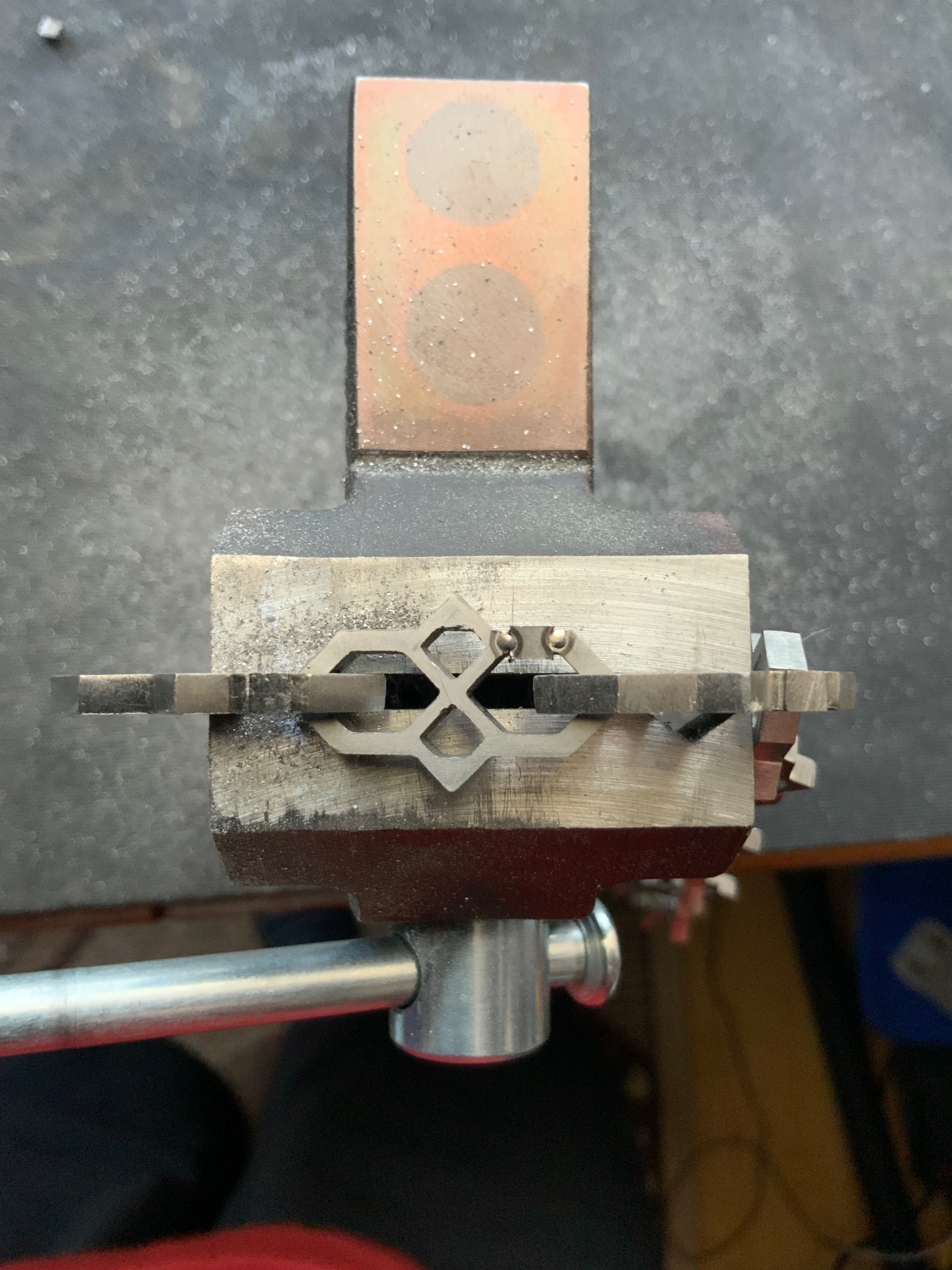 Precyzyjne mocowanie metalowego elementu w imadle, gotowego do obróbki. Widoczne narzędzia i detale powierzchni, wskazujące na etap pracy nad metaloplastyką.