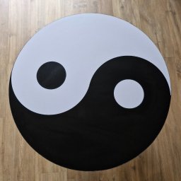 PatentMeble Patryk Jarkowski - Okrągły stolik kawowy z motywem Yin Yang na drewnianej podłodze. Kontrastowe kolory i minimalistyczny design.