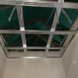 Stelaż sufitu podwieszanego z płyt kartonowo-gipsowych, widoczne profile metalowe, izolacja oraz fragment ściany z nałożonym gładzią.