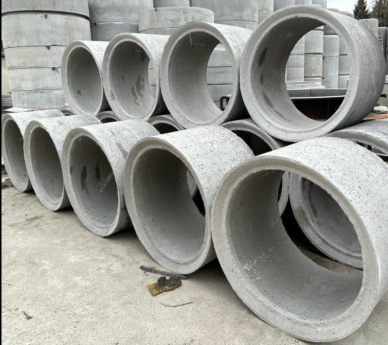 Szare betonowe kręgi ułożone warstwami, widoczne z bliska, z drobnymi niedoskonałościami powierzchni i różnicami w odcieniach szarości.