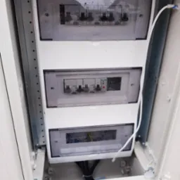Rozdzielnia elektryczna z zamontowanymi bezpiecznikami Legrand, widoczna instalacja przewodów. Skrzynka zabezpieczona przed wilgocią. Element instalacji elektrycznej.