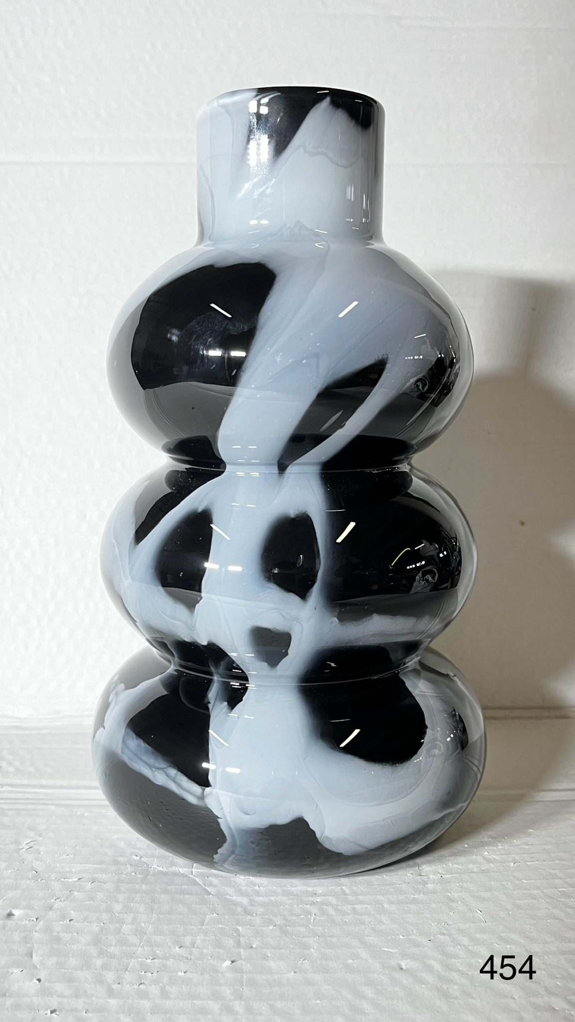 Czarno-biały, szklany wazon dekoracyjny z efektem marmuru, stojący na białym tle. Wyjątkowy element wystroju z Szebnie.