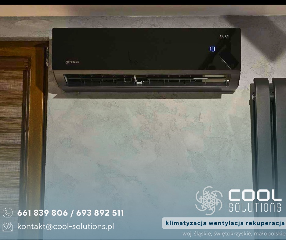 Czarny klimatyzator Rotenso Elis zamontowany na ścianie o fakturze betonu, obok grzejnika. Widoczny numer 18 na wyświetlaczu. Ujęcie z bliska.