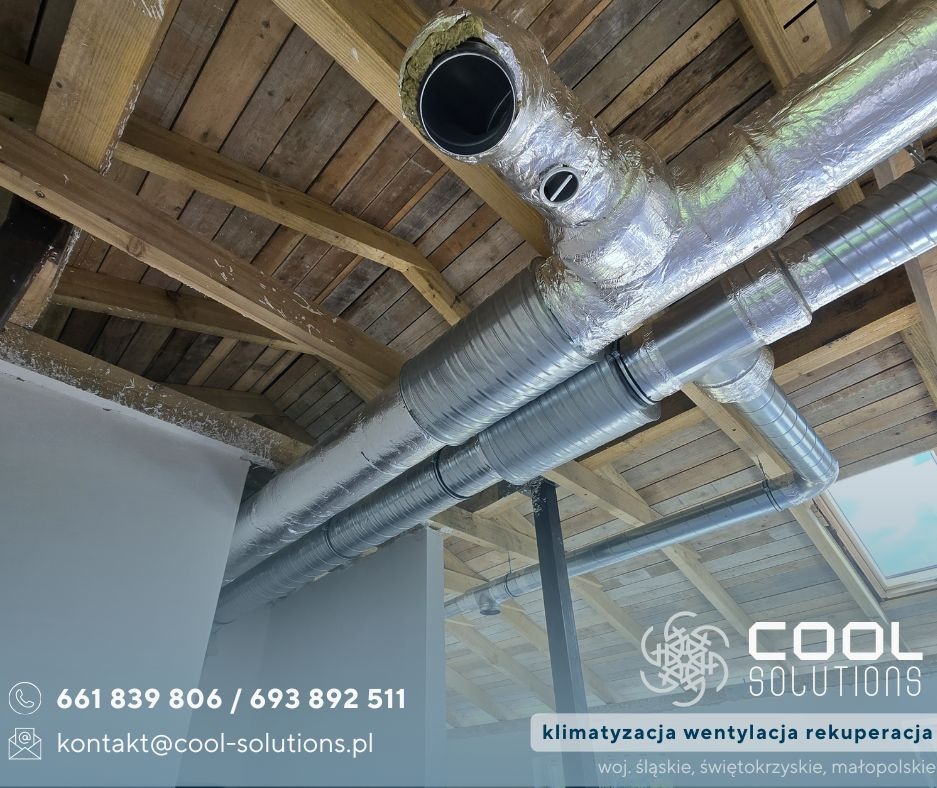 Srebrne rury wentylacyjne pod drewnianym stropem, widok z dołu. Instalacja w trakcie montażu, izolacja na rurach.