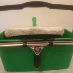 Zielone wiadro z uchwytem, wewnątrz mop do mycia okien i ściągaczka Unger. Sprzęt do mycia okien.
