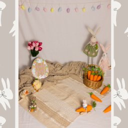 Spizoczko - Aranżacja wielkanocna z pluszowymi królikami, pisankami, koszykiem marchewek i dekoracjami na beżowym tle z motywem królików.