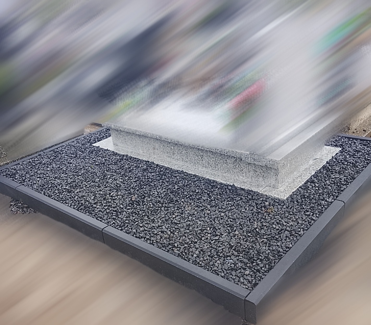 Granitowa oprawa pomnika: ciemne kamienie i obrzeża tworzą estetyczną przestrzeń wokół nagrobka, podkreślając jego formę.