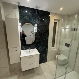 M&D Remont4everyone Mykola Petruniv - Wykończona łazienka z marmurowymi płytkami, kabiną prysznicową i umywalką z szafką. Na ścianie dekoracyjny panel w odcieniach zieleni i czerni. W lustrze odbicie osoby.