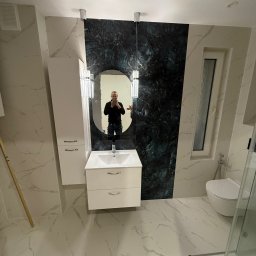 M&D Remont4everyone Mykola Petruniv - Nowoczesna łazienka z marmurowymi płytkami, owalnym lustrem i ciemnozieloną ścianą. Widoczna toaleta i kabina prysznicowa. W lustrze odbija się osoba robiąca zdjęcie.