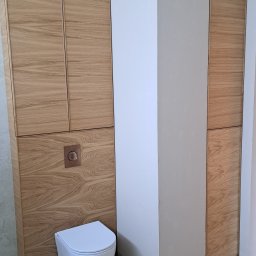 DesignLAB Manufaktura Mebli - Nowoczesna łazienka z drewnianymi szafkami na wymiar w zabudowie, wisząca toaleta i minimalistyczny design. Widoczne detale wykończenia i armatura.