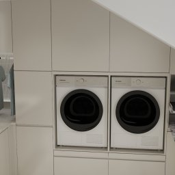 Projektowanie wnętrz Anna Żyjewska-Bas - Funkcjonalna pralnia w zabudowie: pralka, suszarka, deska do prasowania i wieszak na ubrania. Minimalistyczny design w jasnych, stonowanych barwach.