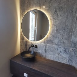 Karo - Nowoczesna łazienka z okrągłym lustrem LED, czarną umywalką nablatową i szarą marmurową ścianą. Minimalistyczny design, eleganckie wykończenie.