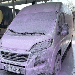 MATBUS Mateusz Stefaniak - Bus w pianie podczas mycia w samoobsługowej myjni. Widoczny numer stanowiska '02' i uchwyt na dywaniki. Piana pokrywa całą karoserię, tablica rejestracyjna widoczna.