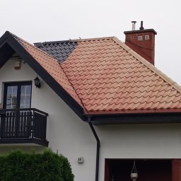ATADOM SPÓŁKA Z OGRANICZONĄ ODPOWIEDZIALNOŚCIĄ - Częściowo odnowiony dach z dachówką ceramiczną i komin na tle nieba w Andrzejki-Tyszki. Widoczna część dachu w kolorze czarnym i część w kolorze czerwonym.