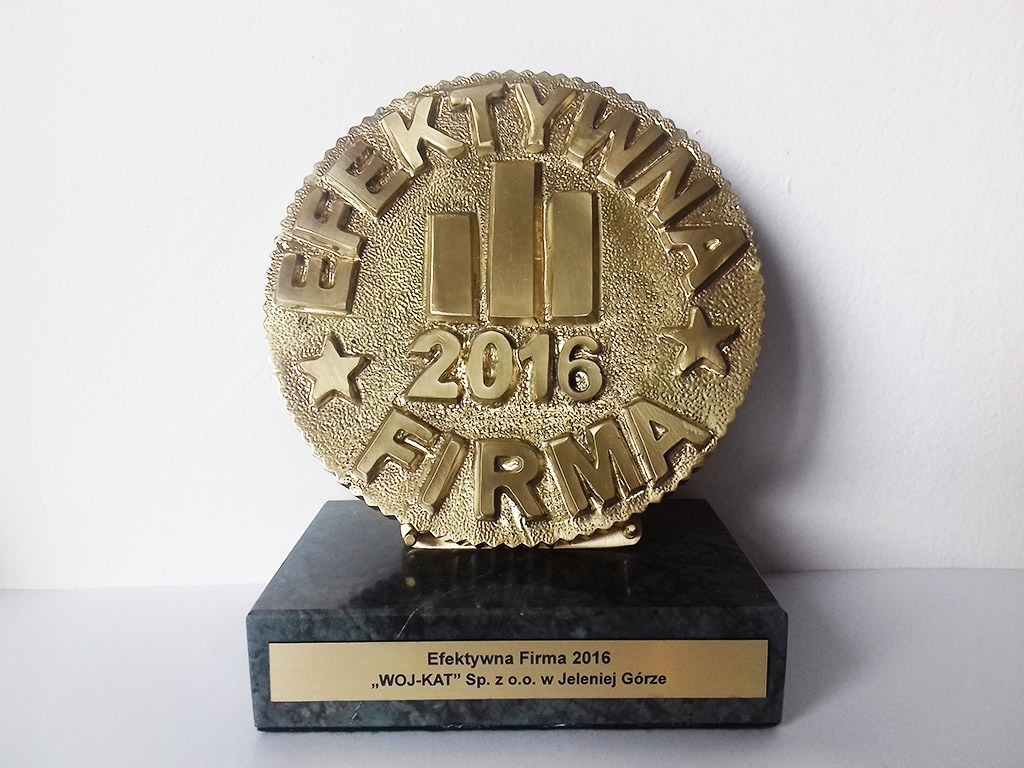 Złota statuetka 'Efektywna Firma 2016' na marmurowej podstawie z tabliczką 'WOJ-KAT' Sp. z o.o. w Jeleniej Górze, na białym tle.