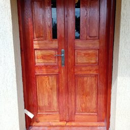 Fjordis - Lakierowane, dwuskrzydłowe drzwi wejściowe z szybkami, świeżo po renowacji w Aleksandrowie Kujawskim. Widoczne narzędzia pracy i niedoskonałości wykończenia.