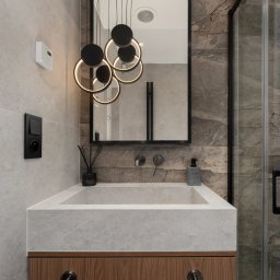 Gawra Studio Projektowe Justyna Miś-Nalepka - Nowoczesna łazienka z umywalką z szarego kamienia, drewnianą szafką i czarną armaturą. Nad umywalką lustro w czarnej ramie i designerska lampa wisząca.