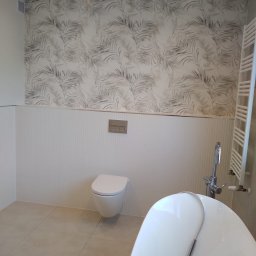 Mykola Kreshchyk - Elegancka łazienka: biała wanna, podwieszana toaleta, grzejnik drabinkowy i ściana z motywem liści. Nowoczesny design i jasna kolorystyka.