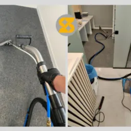 Czyszczenie wykładziny biurowej szarym odkurzaczem piorącym z czarnym wężem. Pracownik w czarnej rękawicy. Widoczny sprzęt do czyszczenia tapicerki.