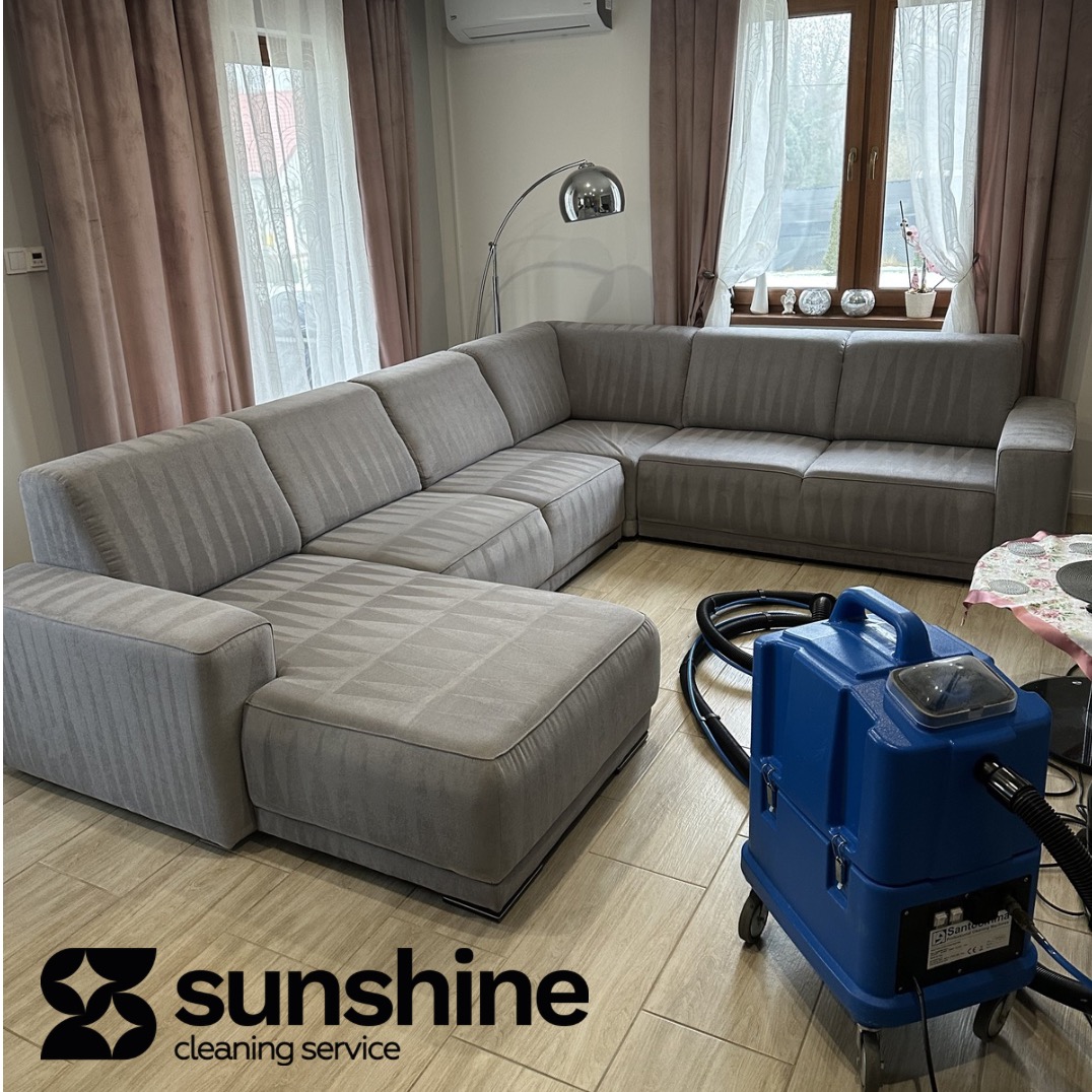 Wyczyszczona, modułowa sofa narożna w salonie z parkietem. Widoczny profesjonalny sprzęt czyszczący. Świeże ślady po praniu na tapicerce.